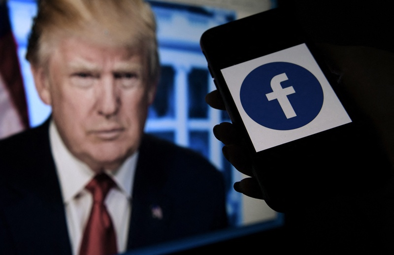 In this file photo illustration taken on May 04, 2021, a phone screen displays a Facebook logo with the official portrait of former US President Donald Trump on the background in Arlington, Virginia. – AFPn