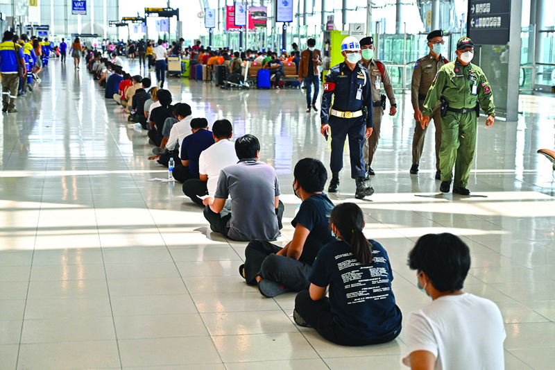 BANGKOK: Airport workers wait in a queue to receive vaccinations against the COVID-19 coronavirus while security personnel walk by at the departure terminal of Suvarnabhumi Airport in Bangkok yesterday.  - AFPn