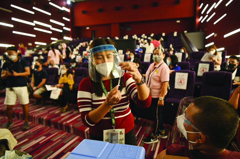 MANILA: A health worker prepares a vial of Chinese Sinovac vaccine against COVID-19 coronavirus disease inside a movie theatre turned into a vaccination center in Taguig City suburban Manila yesterday.-AFPn