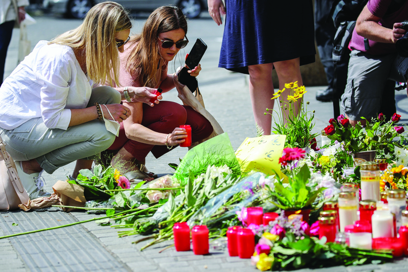 WURZBURG: Two women place a candle at a makeshift memorial of flowers and candles in tribute to the victims of a deadly attack in the city center of Wuerzburg, southern Germany, yesterday.-AFPnn
