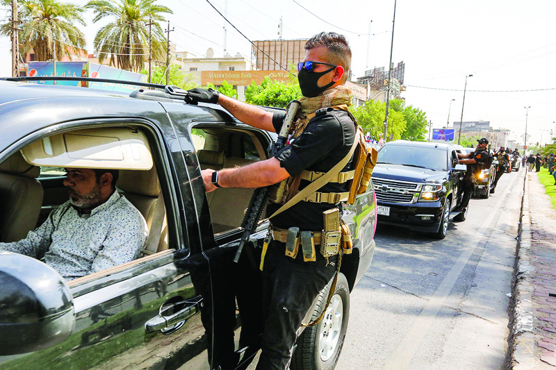 BAGHDAD: Members of Iraq's Hashed Al-Shaabi (Popular Mobilization) paramilitary forces ride in vehicles driving in a symbolic funerary parade in the capital Baghdad Tuesday in remembrance of those killed in a US raid against one of the Hashed's brigades. - AFPnn