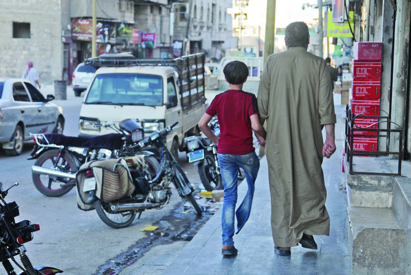 AL-BAB, Syria: Displaced Syrian Mustafa Shaaban Abu Khalil walks alongside his son who lost a leg due to bombing, on a street in the rebel-held city of al-Bab northwest of Aleppo in northern Syria. - AFPnnn
