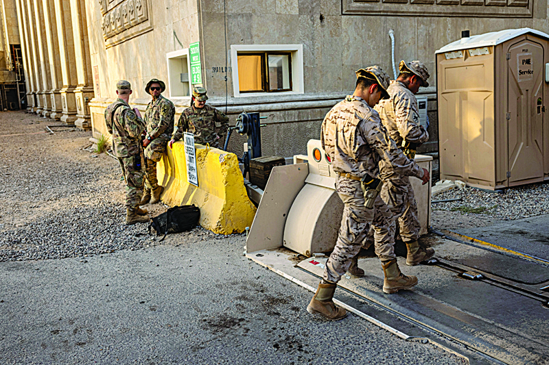 BAGHDAD: US Army soldiers watch as fellow coalition soldiers pass by near the entrance to the International Zone in Baghdad.-AFPn