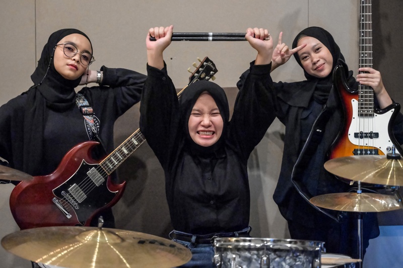 In this picture members of the Indonesian heavy metal band Voice of Baceprot (VOB), guitarist and vocalist Firda Marsya Kurnia (left), drummer Euis Siti Aisah (center) and bassist Widi Rahmawati (right) pose for photos after a practice session in Jakarta. – AFPn