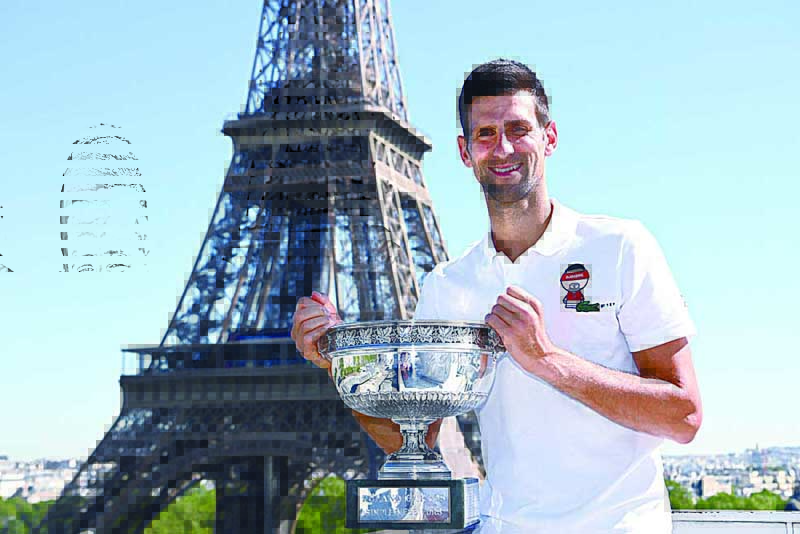 PARIS: Serbia's Novak Djokovic poses with the trophy in front of the Eiffel tower yesterday during a photo call, a day after winning the Roland Garros 2021 French Open tennis tournament. - AFP n