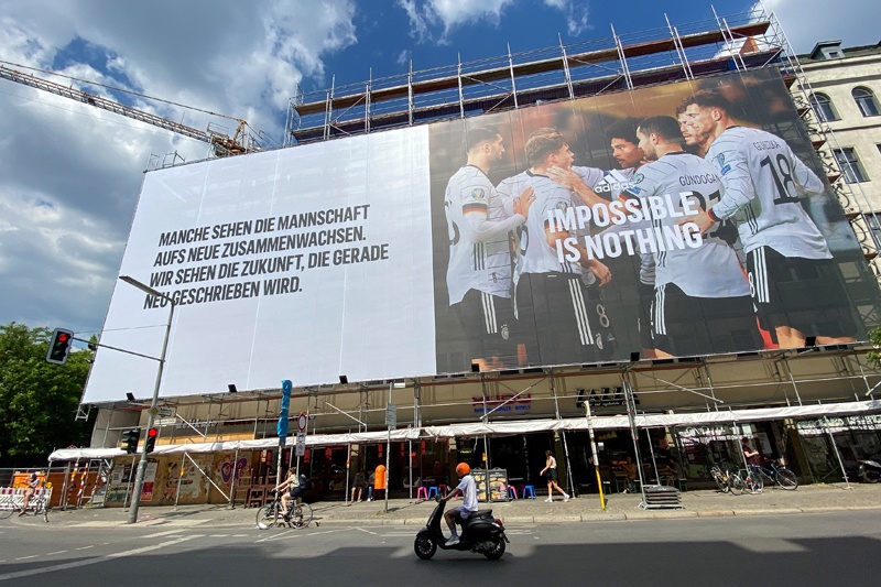 BERLIN: A person rides a scooter past a building under construction covered in a massive billboard with an advertisement featuring the German national football team ahead of the upcoming UEFA Euro 2020 football championships in Berlin's Kreuzberg district on Sunday. – AFPnn