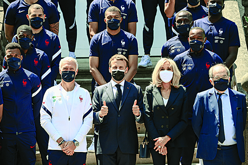 CLAIREFONTAINE-EN-YVELINES: France's coach Didier Deschamps (second left), French President Emmanuel Macron (center), his wife Brigitte Macron (second right) and French Football Federation (FFF) president Noel Le Graet (right) pose for a group picture with France's players before a lunch in Clairefontaine-en-Yvelines yesterday ahead of the UEFA EURO 2020 football competition. - AFPnn