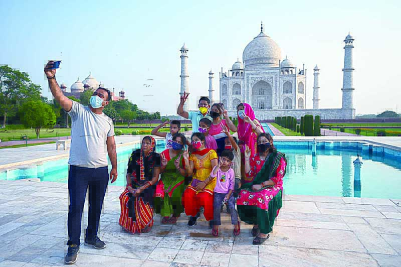 AGRA: A group of tourists take souvenir photos at the Taj Mahal after it reopened to visitors following authorities easing COVID-19 coronavirus restrictions in Agra yesterday. - AFPn