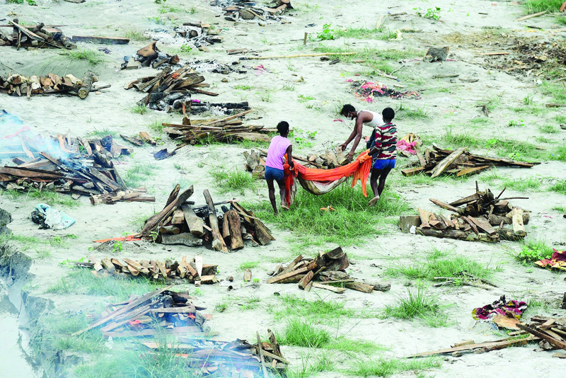 ALLAHABAD, India: Municipal corporation workers prepare to cremate a body buried in a shallow grave on the banks of the Ganges River .-AFP n