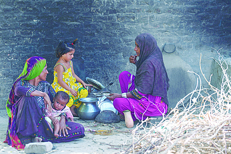 DAHARKI: In this picture taken on June 8, 2021 Habiba Mai (R), wife of school teacher Ali Nawaz, who helped with the rescue efforts of the train collision, prepares tea for her family at her home near the train accident site in Daharki of Sindh Province. -- AFPn