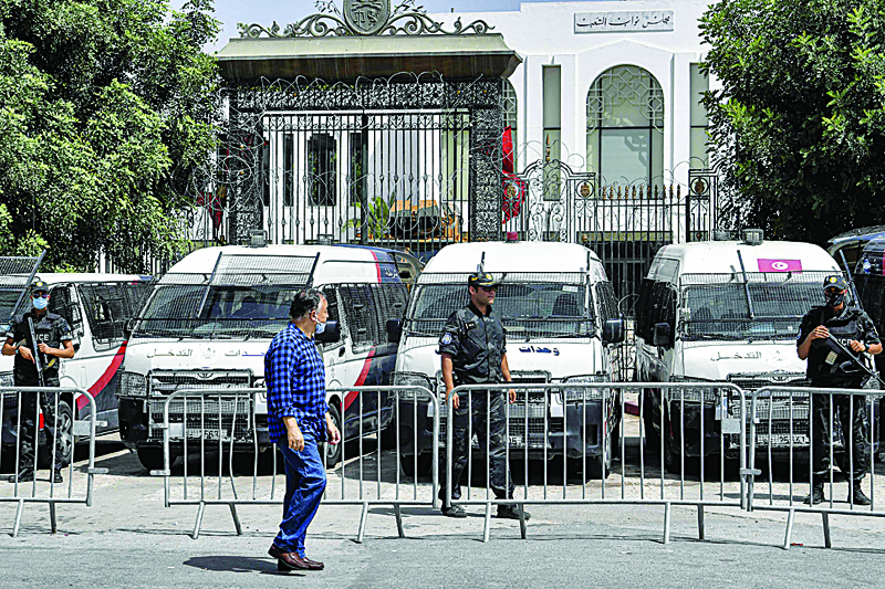 Tunis : A man walks past members of Tunisia's security forces standing guard outside parliament headquarters in Bardo in Tunis on July 31, 2021. -AFP n
