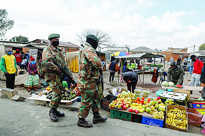 ALEXANDRA, SOUTH AFRICA : People stand and watch at a food marke as a members of the South African Defence Force (SANDF) patrol their area in Alexandra township, Johannesburg on July 15, 2021. Stores and warehouses in South Africa were hit by looters on July 13, despite the troops President Cyril Ramaphosa deployed to try to quell unrest. As pillaging erupted in the economic capital of Johannesburg and the southeastern province of KwaZulu-Natal, South Africa's main opposition accused radicals of stoking the unrest. - AFP