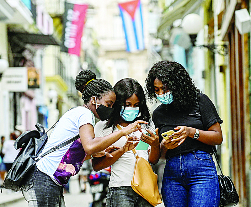 HAVANA: Women use their phones in a street on Wednesday. - AFP nn