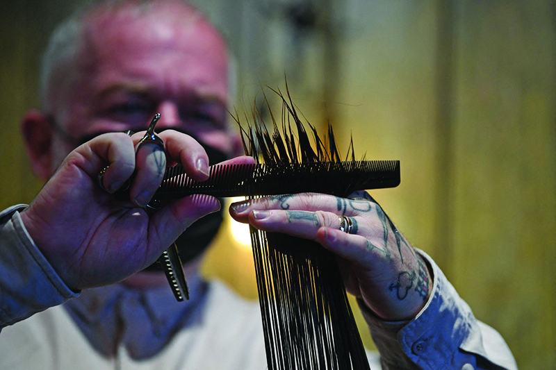 Hair salon owner and hairdresser Adam Reed cuts the hair of a client at his salon in Spitalfields, east London, on July 1, 2021, before collecting the hair for recycling. – AFP photosn
