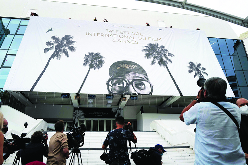 Journalists take images as workers install a giant banner at the Palais des Festivals et des Congres in Cannes, southeastern France, two days before the start of the 74th Cannes Film Festival. — AFP n