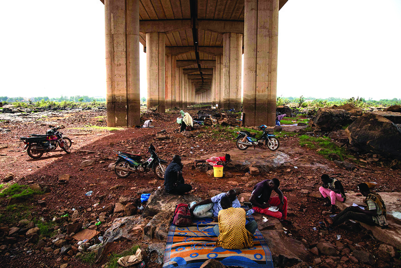 Men perform a traditional ceremony under the 'Third Bridge', next to the Niger river, in Bamako. - AFP n