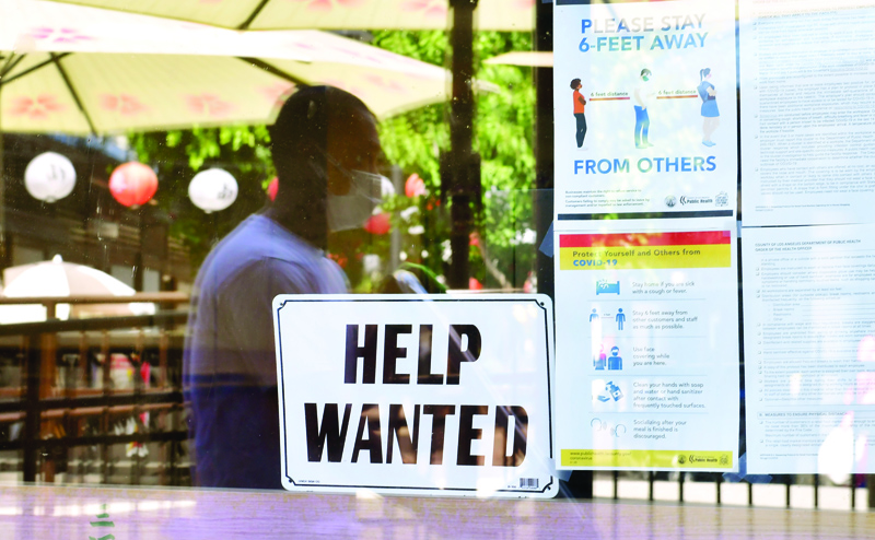 LOS ANGELES: In this file photo, a 'Help Wanted' sign is posted beside Coronavirus safety guidelines in front of a restaurant in Los Angeles, California. - AFPnn