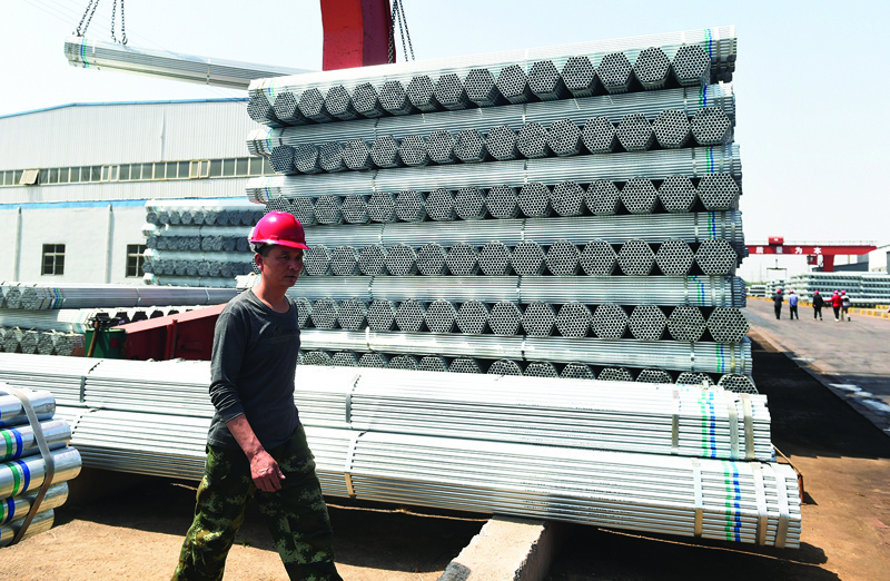 ZOUPING, China: This file photo taken on April 17, 2018 shows a worker walking past steel pipes at a factory in Zouping in China's eastern Shandong province. European Commission will announce carbon border tax proposal tomorrow to meet the EU's environmental policy and objectives. - AFP nn