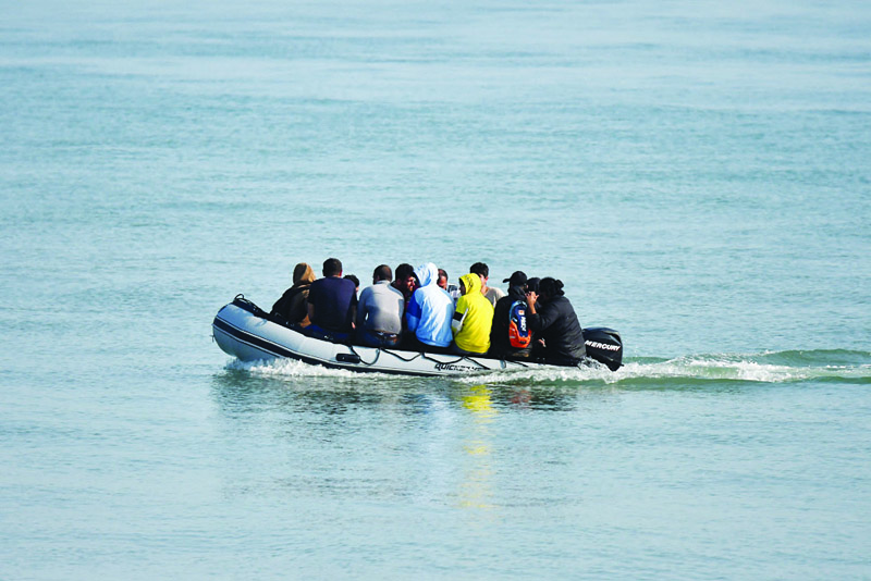 DEAL, UNITED KINGDOM : File photo shows migrants travel by inflatable boat as they reach the shore near Deal on the south east coast of England. Britain announced it will seek harsher sentences for migrants caught entering the country without permission. - AFPnn