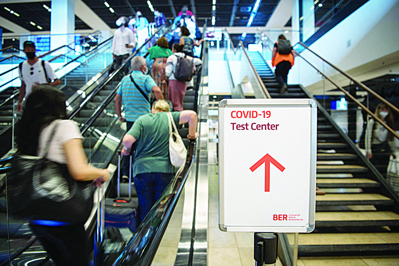 BERLIN: Passengers stand on an escalator next to a sign pointing to a test center for COVID-19 coronavirus at the BER Willy Brandt airport in Brandenburg, near Schoenefeld und Berlin, yesterday. - AFPn