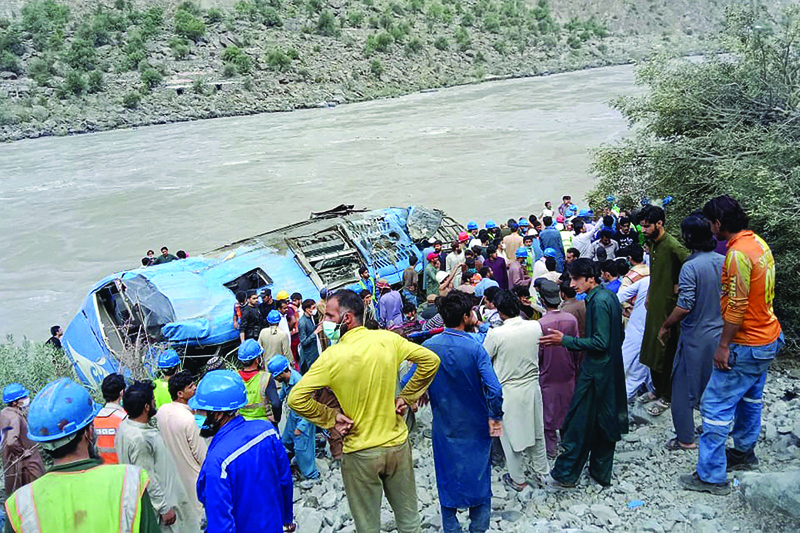 Rescue workers and onlookers gather around a wreck after a bus plunged into a ravine following a bomb explosion in Kohistan district of Khyber Pakhtunkhwa province yesterday. - AFP n