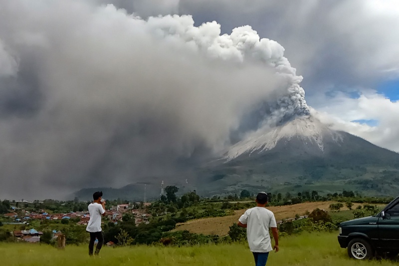 KARO, Indonesia: People look on as Mount Sinabung erupts spewing a massive column of smoke and ash yesterday. -  AFP n