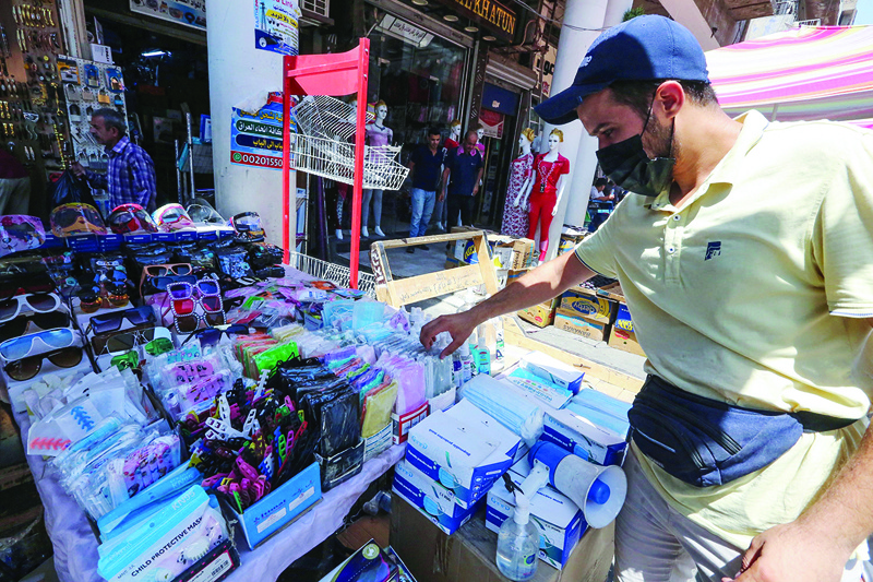 BAGHDAD: An Iraqi shopkeeper arranges facemasks at a stall on a market street yesterday. - AFP n