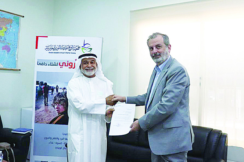 KUWAIT: Sheikh Abdullah Al-Nouri Charity's Chairman Jamal Al-Nouri (left) and UNHCR bureau representative in Kuwait Dr Samer Haddadeen shake hands after signing the accord. - KUNAn