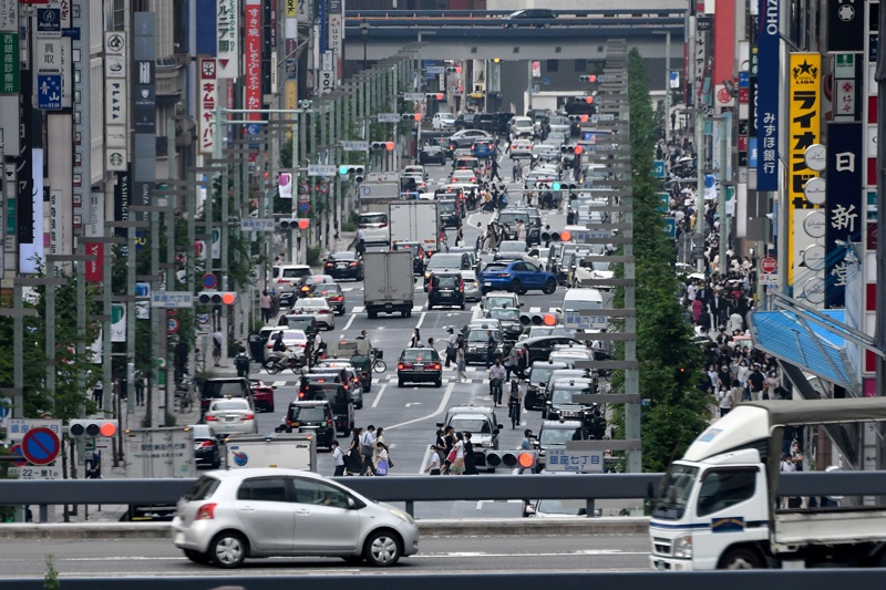 TOKYO: Vehicles and pedestrians move through a street in Tokyo's Ginza shopping district yesterday. – AFPn