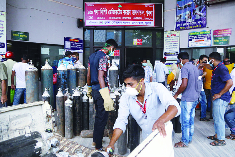 KHULNA, Bangladesh: In this picture taken on July 2, 2021 Men unload medical oxygen cylinders at the entrance of a government hospital dedicated to treat COVID-19 patients in Khulna. - AFPn
