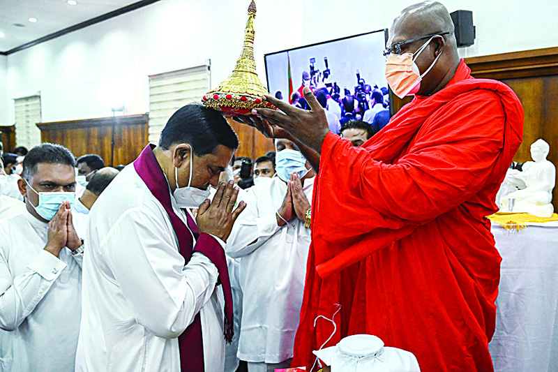 COLOMBO: Newly appointed Sri Lanka's Minister of Finance Basil Rajapaksa (center) receives blessing from a Buddhist monk after signing documents during his swearing-in ceremony at the Ministry of Finance office in Colombo yesterday. - AFP n