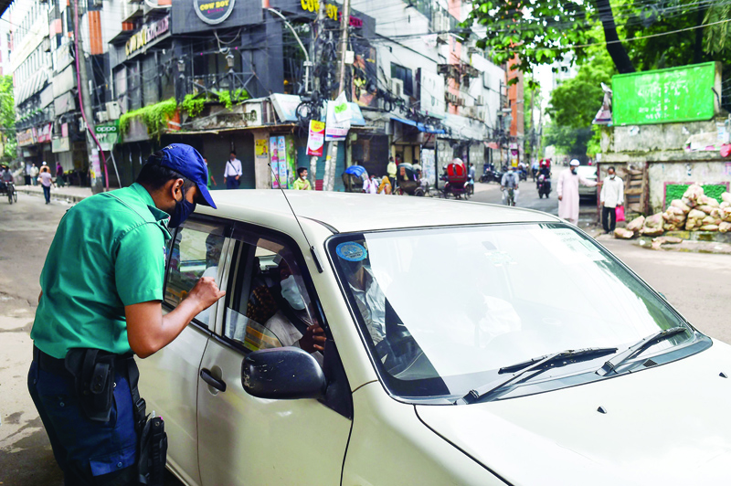 DHAKA: A policeman questions a motorist at a checkpoint in Dhaka yesterday, as the country went into a strict COVID-19 Coronavirus lockdown. - AFPn