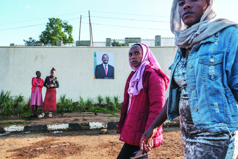 BONGA, Ethiopia: People walk in front of a sign depicting Ethiopia's Prime Minister Abiy Ahmed at the entrance to Bonga University, in the town of Bonga, 100 km southwest of the city of Jimma, Ethiopia.-AFPn