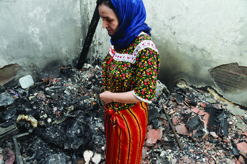 TIZI-OUZOU, Algeria: An Algerian woman dressed in a traditional outfit stands amidst the charred debris of her home that burned down during wildfires in the Ait Daoud area of northern Algeria, Friday.-AFPn