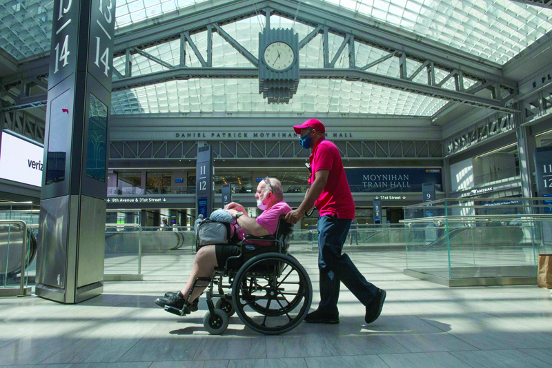 NEW YORK: A man with his mask partially on is pushed on a wheel chair through Penn station in New York Monday. - AFPn