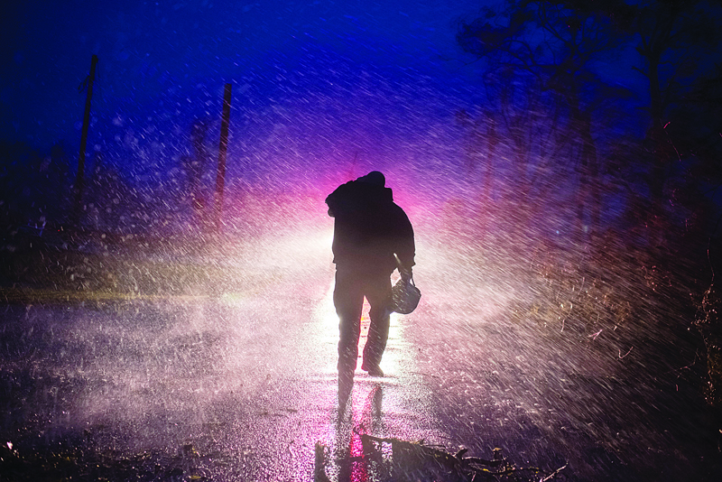 BOURG: Montegut fire chief Toby Henry walks back to his fire truck in the rain as firefighters cut through trees on the road in Bourg, Louisiana as Hurricane Ida passes Sunday.-AFPn