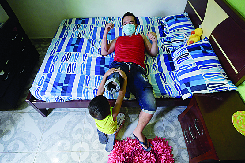 CATATUMBO, Colombia: Ivan Rodriguez, 25, victim of a landmine, does physical therapy with his stepson Moises at their house in Catatumbo, Norte de Santander department, Colombia.-AFPn