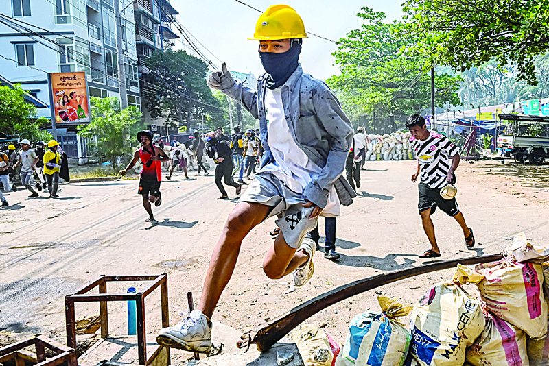 YANGON: A protester jumps over a makeshift barricade during a crackdown by security forces on a demonstration against the military coup in Yangon's Thaketa township. - AFPn