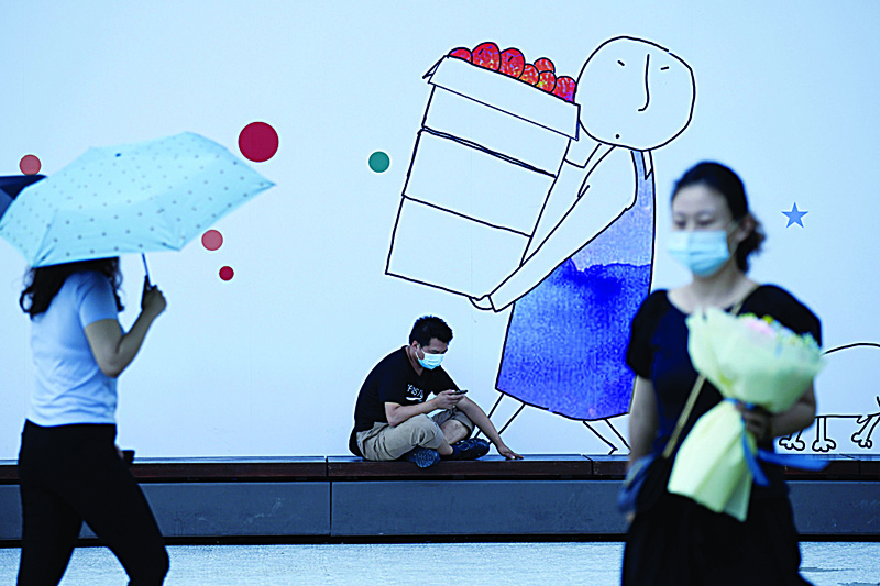 This file photo a man wearing a face mask using his mobile phone in front of an advertising board in Beijing.-AFP photosn