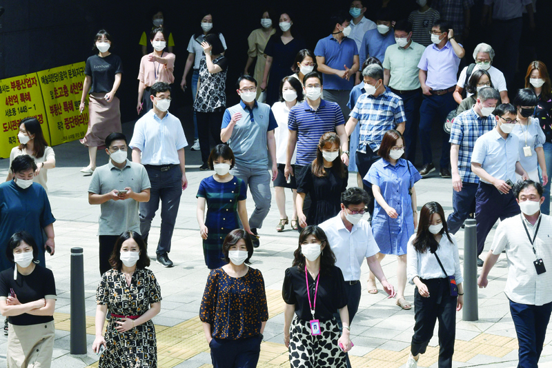 SEOUL: This file photo taken on August 20, 2020 shows people wearing face masks as they prepare to cross a street in Seoul. South Korea has the highest gender wage gap in the OECD club of developed countries. - AFPn
