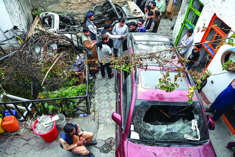 KABUL: Afghan residents and family members of the victims gather next to a damaged vehicle inside a house, day after a US drone airstrike in Kabul Monday.—AFPn