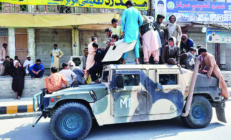 Taleban fighters and local residents sit over an Afghan National Army (ANA) humvee vehicle along the roadside in Laghman province yesterday. - AFP n