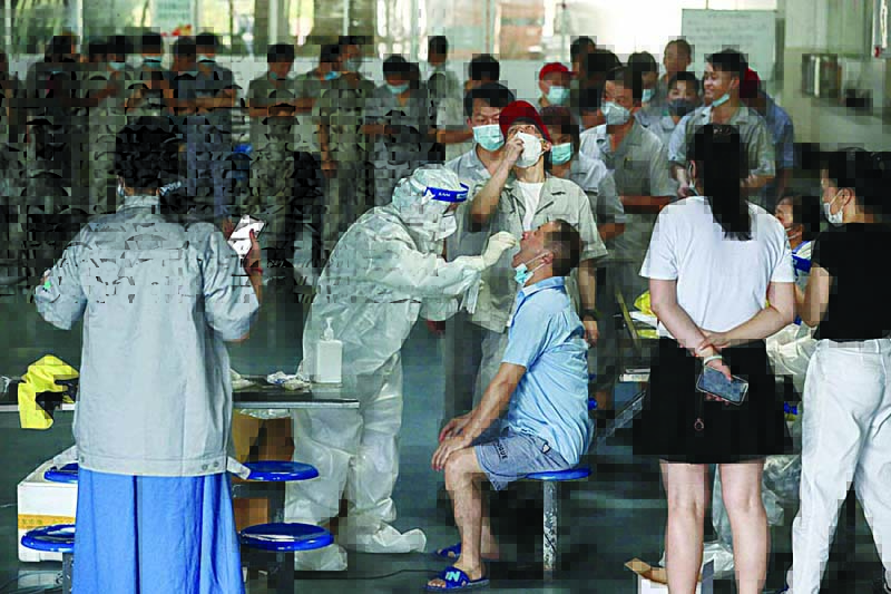 WUHAN: A worker receives a nucleic acid test for COVID-19 at the dining hall of a car parts factory yesterday. - AFP n