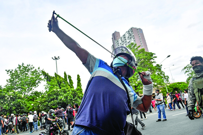 BANGKOK: A pro-democracy protester uses a slingshot against police during a demonstration calling for the resignation of prime minister Prayut Chan-O-Cha over the Thai government’s handling of the COVID-19 coronavirus crisis, in Bangkok Friday. — AFPn
