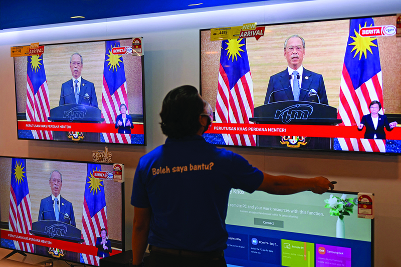 KUALA LUMPUR: A man watches a television on display at a shopping mall store as Malaysian Prime Minister Muhyiddin Yassin announces his resignation as he addresses the nation during a live telecast in Kuala Lumpur yesterday. - AFPnn