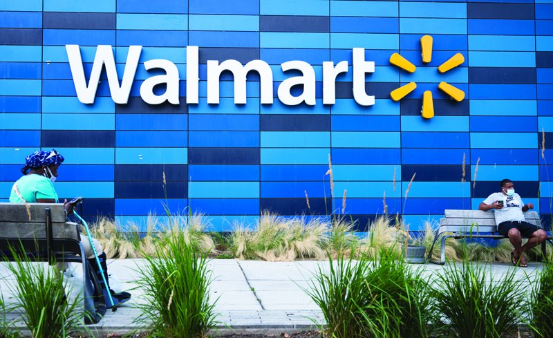 WASHINGTON: People sit outside a Walmart store in Washington, DC. Walmart lifted its full-year forecast yesterday following another solid performance at its US stores in the second quarter.-AFPnn