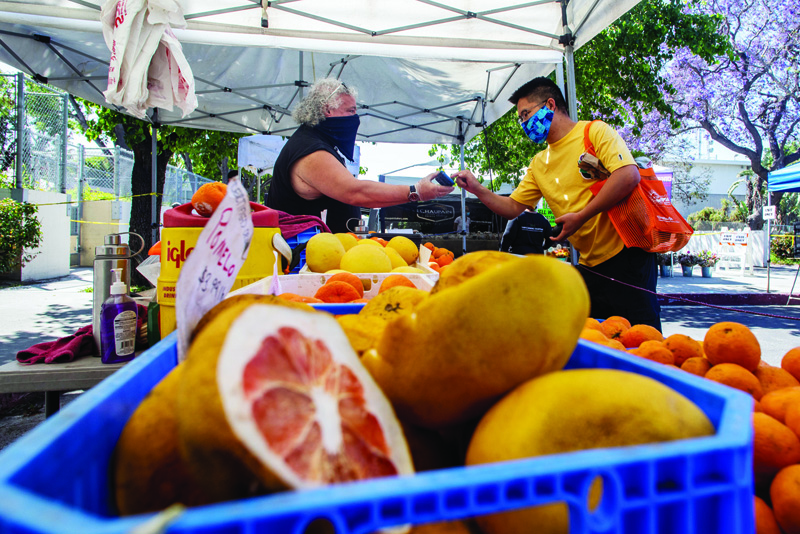 SANTA MONICA,US: In this file photo a shopper pays for oranges in a citrus tent at the West LA Farmer's Market in Santa Monica, California. - AFPn