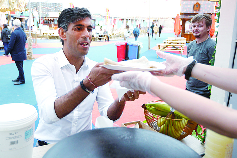 LONDON: Britain's Chancellor of the Exchequer Rishi Sunak gestures as he takes a pancake from a stall at the London Wonderground comedy and music festival venue in London.-AFPn