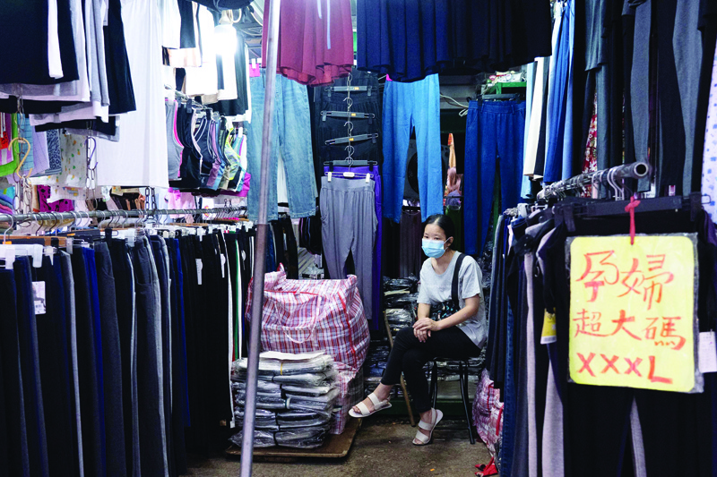 HONG KONG : This photo taken on August 15, 2021 shows a vendor waiting for customers at a stall selling trousers in Hong Kong. – AFPn