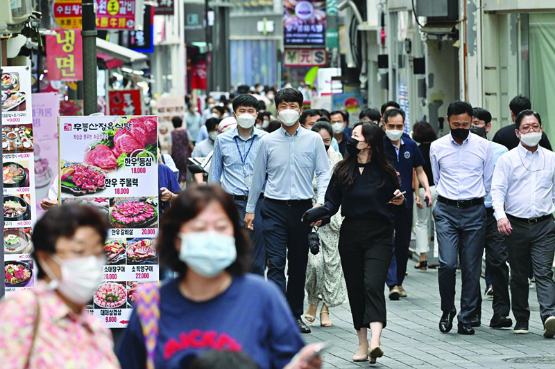 SEOUL: Pedestrians walk through the Myeongdong shopping district in Seoul yesterday, after South Korea's central bank announced first rate hike in three years. - AFPn